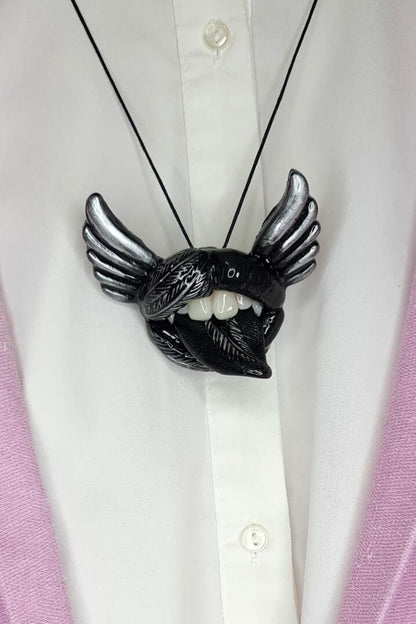 Black lips with fangs  and silver accents, embraced by the allure of Gothic jewelry, adorned with black angel wings,  Wearable Artwork by ioArtStudio