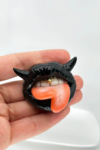 Handmade polymer clay black lips with split tongue, horns, and smile piercing, a unique and eye-catching wearable art by ioArtStudio